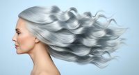 Woman with long, flowing silver-gray wavy hair in profile against light blue background. Suitable for hair care, beauty products, aging gracefully, and salon services.