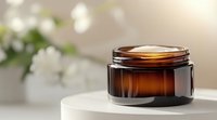 Amber glass cosmetic jar on white marble surface with soft bokeh background and white flowers, luxury skincare product packaging for beauty brands.