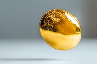 Shiny golden round metal coin or medallion with textured surface floating against blurred gray background, macro photography showing luxury detail and reflection.