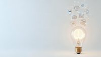 Glowing light bulb with innovation icons floating above on white background representing creative ideas and business solutions for presentations.