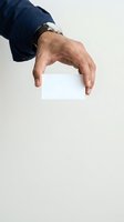 Mature male hand holding blank white card against neutral background, wearing navy sleeve and wristwatch. Suitable for business, marketing, and corporate design projects.