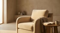Comfortable beige armchair with cushion in minimalist interior space, suitable for home decor, furniture design, and lifestyle publications.