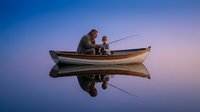Father and son fishing together from wooden boat on calm lake at sunset with purple sky reflection creating peaceful family bonding moment outdoors.
