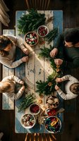 Family making Christmas wreaths together at rustic wooden table with evergreen branches, cranberries and festive decorations from overhead view.