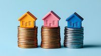 Colorful miniature houses placed on stacks of coins against blue background, representing real estate investment, property market and mortgage costs.