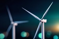 Modern wind turbines against blurred turquoise background with bokeh lights, representing renewable energy and sustainable power generation technology.