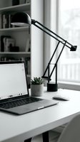 Modern home office workspace with black adjustable desk lamp, laptop computer and small succulent plant on white desk near window for productivity and work.