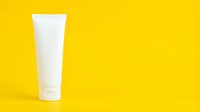 White cosmetic tube isolated on bright yellow background, ready for skincare, sunscreen, or beauty product branding and packaging design.