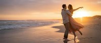 Romantic couple dancing on beach at sunset with golden light reflecting on wet sand and ocean waves creating intimate moment for wedding or anniversary celebration.