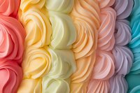 Colorful meringue swirls in pastel rainbow shades of coral, yellow, cream, peach, pink and turquoise create a sweet textured pattern background for dessert designs.