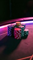 Colorful poker chips stacked on casino table with neon lighting creating atmospheric gambling environment for entertainment and gaming concepts.