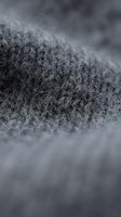 Macro close-up of gray knit fabric texture showing detailed fiber weave and surface pattern, suitable for textile, fashion, and material design projects.