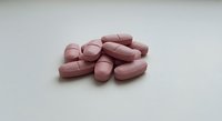 Pink oval tablets scattered on white surface for pharmaceutical and healthcare concepts.