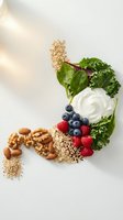 Healthy superfood ingredients with fresh berries, leafy greens, nuts, seeds and yogurt arranged on white background for nutritious meal preparation.