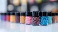 Colorful nail polish bottles arranged in row with pink and blue in focus, showing diamond pattern texture on glass containers against blurred background. Professional manicure collection.