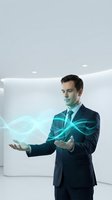 Professional businessman in dark suit manipulating glowing cyan energy waves with hands in modern white office environment for technology and innovation concepts.