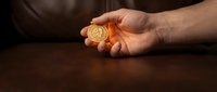 Male hand holding golden coin against dark background, representing wealth, investment, and financial success for business concepts.