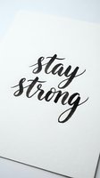 Stay strong written in elegant script lettering on white paper background, isolated design element suitable for motivational posters, greeting cards, wall art, and inspirational merchandise applications.