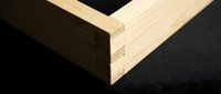 Wooden corner joint detail showing precise craftsmanship and natural wood grain texture for carpentry and woodworking projects.