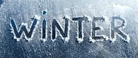 Word WINTER written on a frosted icy window surface covered with snow and ice crystals, cold season concept.