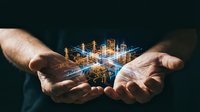 Hands holding glowing digital cityscape with illuminated buildings and network connections, representing urban development, smart city technology, and business innovation.