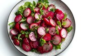 Fresh radish salad with mixed greens and herbs on white plate, healthy vegetarian dish perfect for spring dining and clean eating lifestyle.