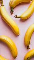Fresh ripe yellow bananas scattered on pink background, creating minimal modern composition for healthy eating and fruit concepts.