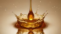 Golden honey drop falling and creating a crown splash, captured in macro detail with warm amber tones for food, beauty, and wellness concepts.