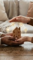 Two hands protecting wooden house model with insurance icons floating above, representing home protection, security and financial planning for real estate investment and property coverage.