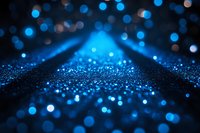 Abstract blue glowing particles and bokeh lights on dark background creating magical atmosphere with depth of field effect and blurred motion.