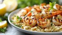 Grilled shrimp with herbs served over pasta, garnished with fresh parsley and lemon slices for gourmet seafood dining experience.