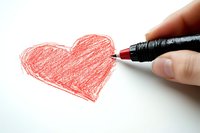 Hand drawing red heart shape with pencil on white paper, close-up view showing creative process and romantic expression. Suitable for Valentine's Day designs and love concepts.