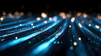 Glowing blue light trails with bokeh effects on black background create dynamic motion and energy pattern for technology and communication designs.