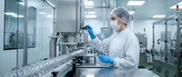 Female scientist in protective gear operating pharmaceutical manufacturing equipment in sterile laboratory facility for drug production and quality control.