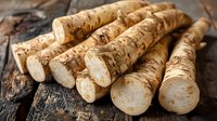 Fresh horseradish roots on rustic wooden background, raw ingredient for spicy condiment used in culinary dishes and traditional medicine.