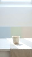 Minimalist ceramic cup on white marble surface with soft natural light and pastel color blocks in background, suitable for home decor and lifestyle design projects.