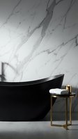 Modern black freestanding bathtub against marble wall with gold accent table holding folded towels and toiletries for luxury bathroom design and spa interior projects.