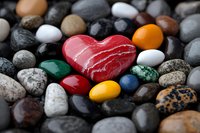 Red heart-shaped stone among colorful pebbles and rocks on dark background, symbol of love and romance, macro photography for Valentine's day cards.