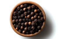 Black peppercorns in wooden bowl on white background, overhead view showing texture and natural spice variation. For food and cooking concepts.