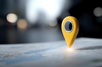 Yellow location pin marker glowing on paper map with blurred city background, navigation and GPS concept for travel and business planning.