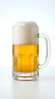 Chilled glass mug filled with golden lager beer and thick foam head, condensation droplets on exterior, isolated on white background for beverage and hospitality use.
