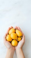 Hands holding fresh yellow lemons on white background, isolated for design use on merchandise, packaging, and promotional materials.