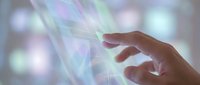 Human hand reaching toward glowing digital energy streams with colorful light effects and bokeh background for technology and innovation concepts.