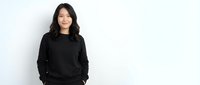 Young Asian woman in black sweater smiling confidently against white background. Professional portrait for business, lifestyle, and casual wear concepts.