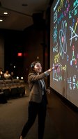 Professional woman teacher presenting complex mathematical formulas on interactive whiteboard in modern classroom setting for education and learning.