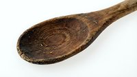 Rustic wooden spoon with natural grain texture and worn patina, ideal for cooking, kitchen decor, and culinary content.