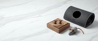 Wooden puzzle box, felt cat tunnel, and toy mouse on white marble surface, minimalist pet accessories and brain teaser game flat lay.