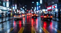 Blurred city street at night with colorful neon lights reflecting on wet pavement, creating bokeh effect from traffic and urban illumination.