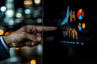 Businessman pointing at financial data analytics charts and graphs on digital screen at night with city lights background.