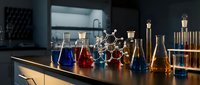 Modern chemistry laboratory with colorful chemical solutions in glass flasks and beakers on wooden table for scientific research and education.